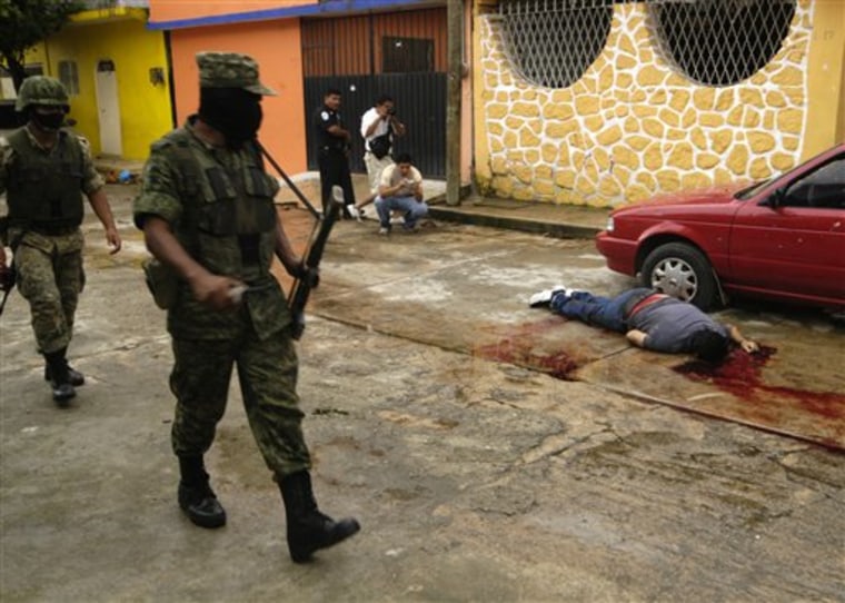 Army soldiers walk by the body of a man lying in the street in Acapulco, Mexico, Thursday Sept. 23, 2010.  Authorities say seven people were killed in a shootout between rival drug gangs. (AP Photo/Bernandino Hernandez)